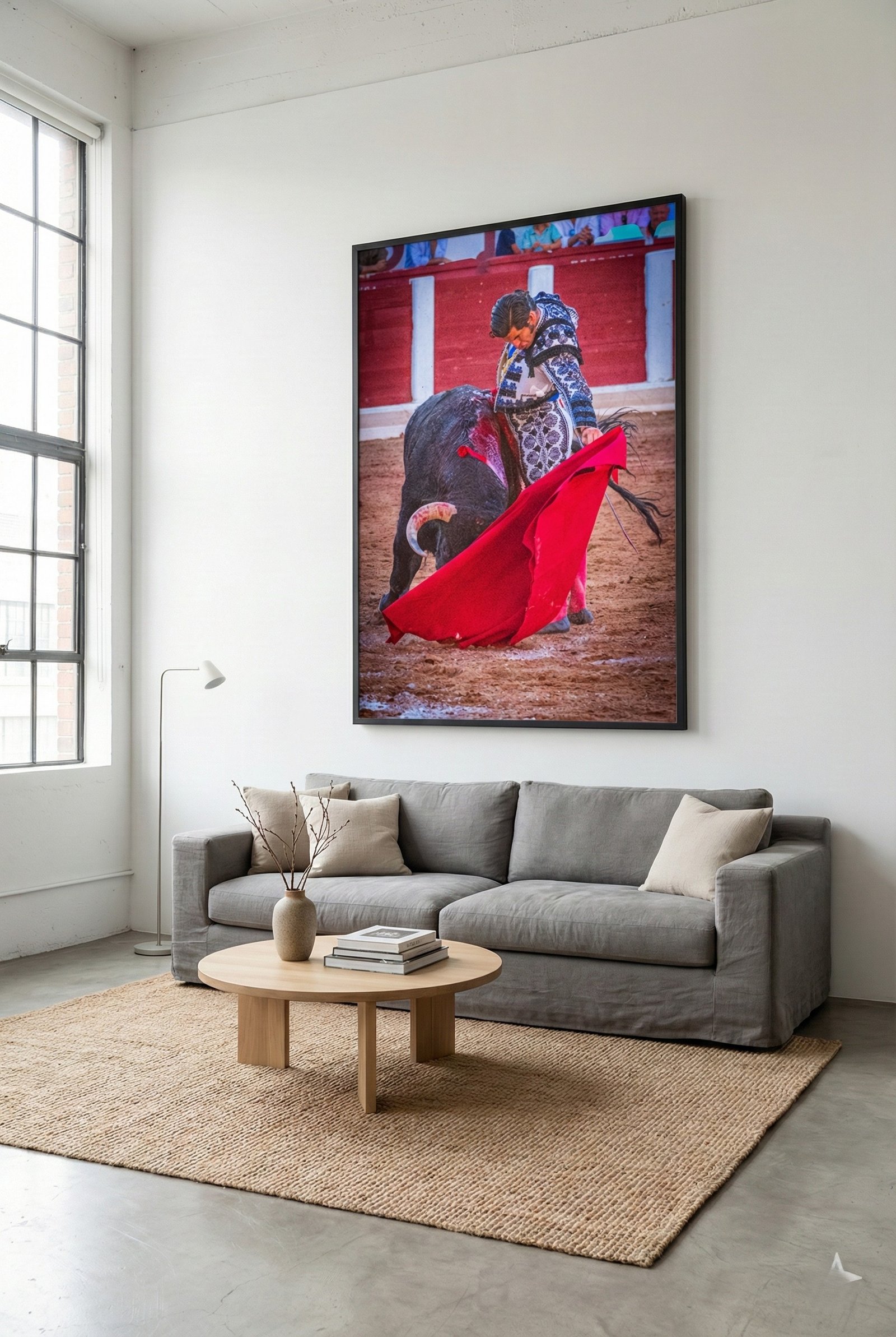 Lámina taurina de alta calidad colgada sobre sofá gris en un salón de estilo minimalista e industrial con paredes blancas.